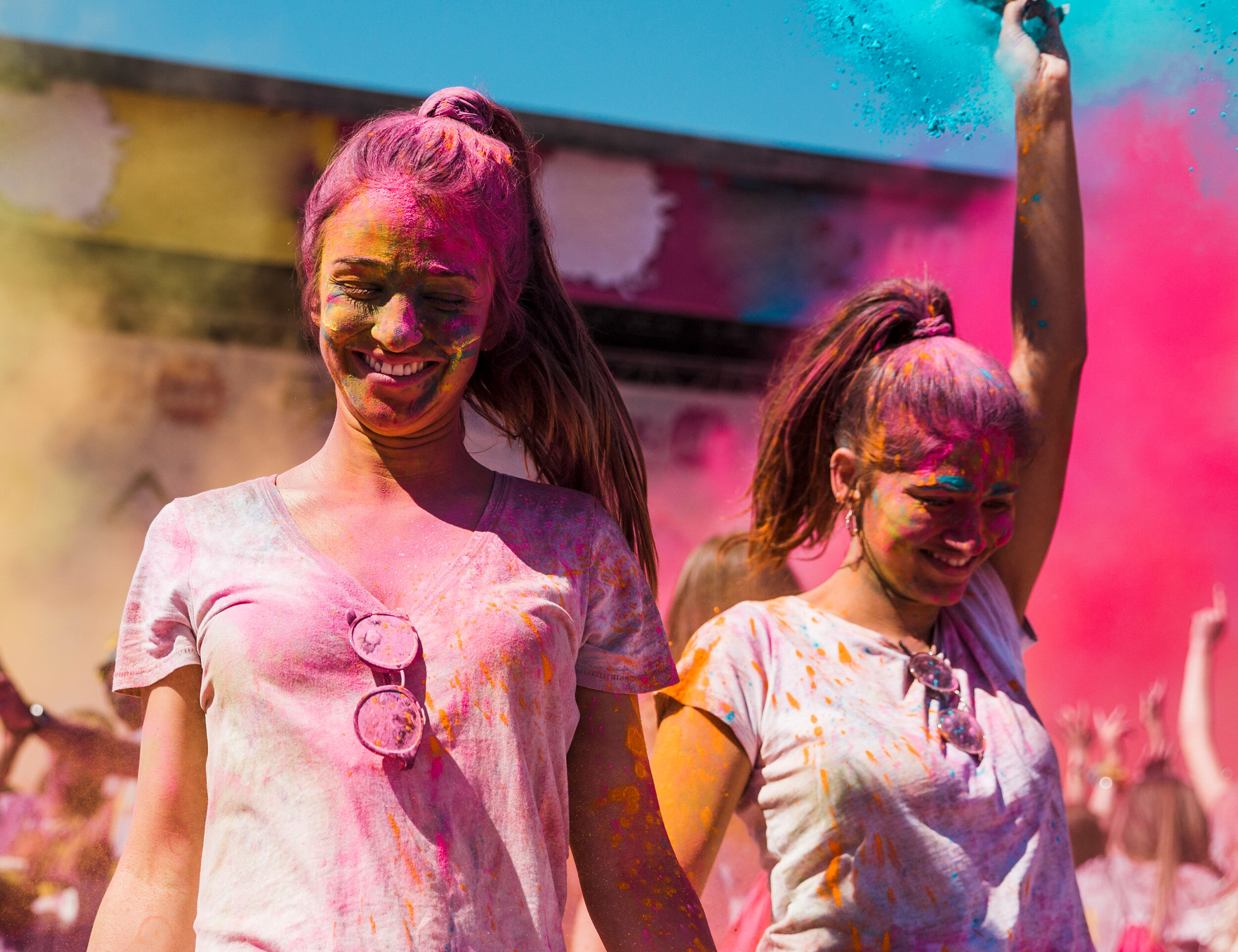 Cheerful Woman Playing Holi with Bright Pink and Yellow Gulal Outdoors